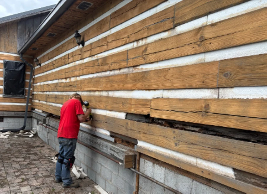 Crew member applying fresh chinking between cabin logs