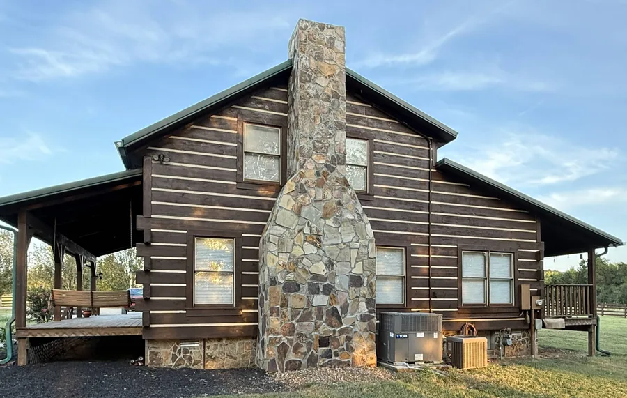 Freshly stained and sealed log cabin with stone chimney