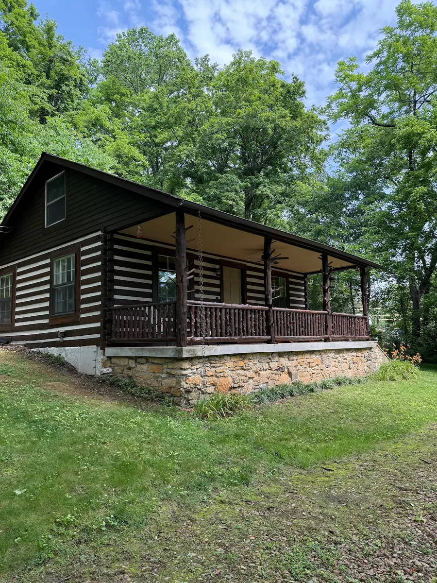 Restored log cabin with covered porch surrounded by trees